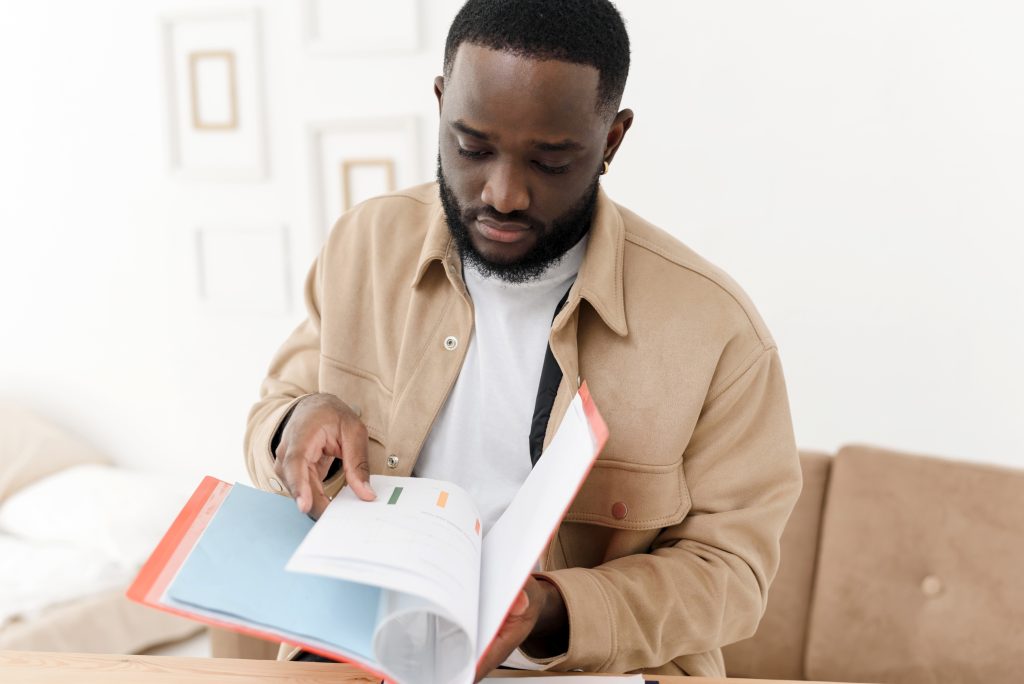 African American young man reads a letter from a bank about financial problems with credit debt. Black man finds out about budget issues, feels frustrated, worried about bad report or bad test results concept