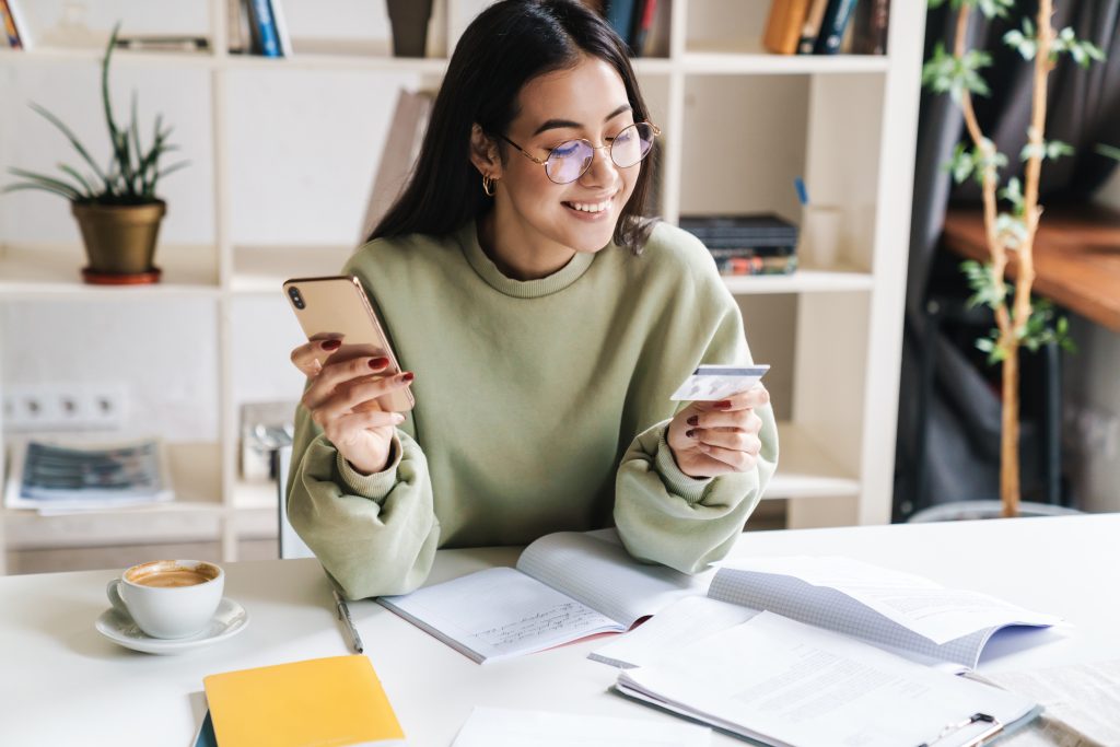 Happy optimistic young girl student holding credit card.