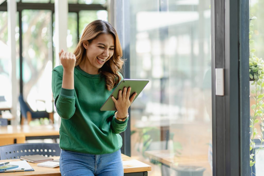 Excited beautiful asian woman looking at digital tablet, young w