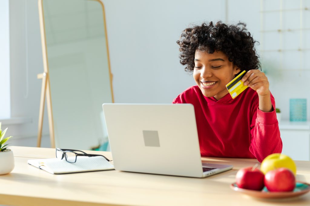 Woman using laptop shopping online paying with gold credit card