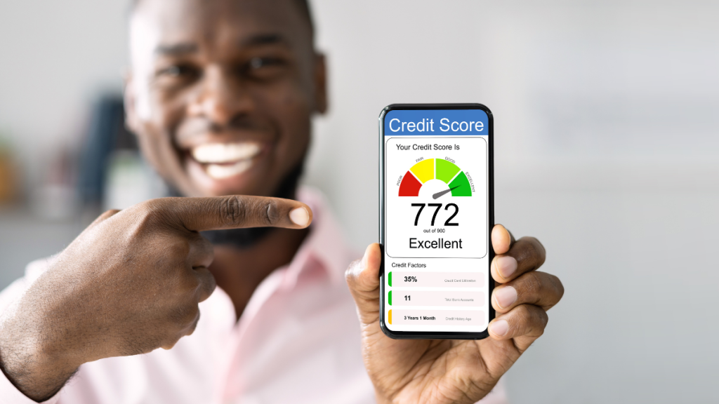 black adult man smiling and pointing at his excellent credit score on his phone. Reflex Mastercard®