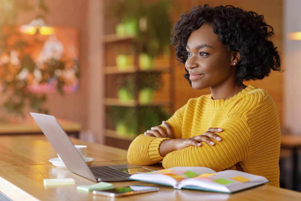 Thoughtful black lady dreaming about new job, sitting at cafe